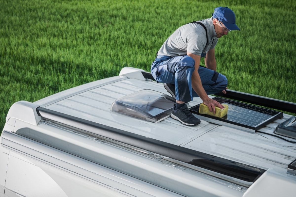 Man Cleaning the Solar Panels on a Van Roof