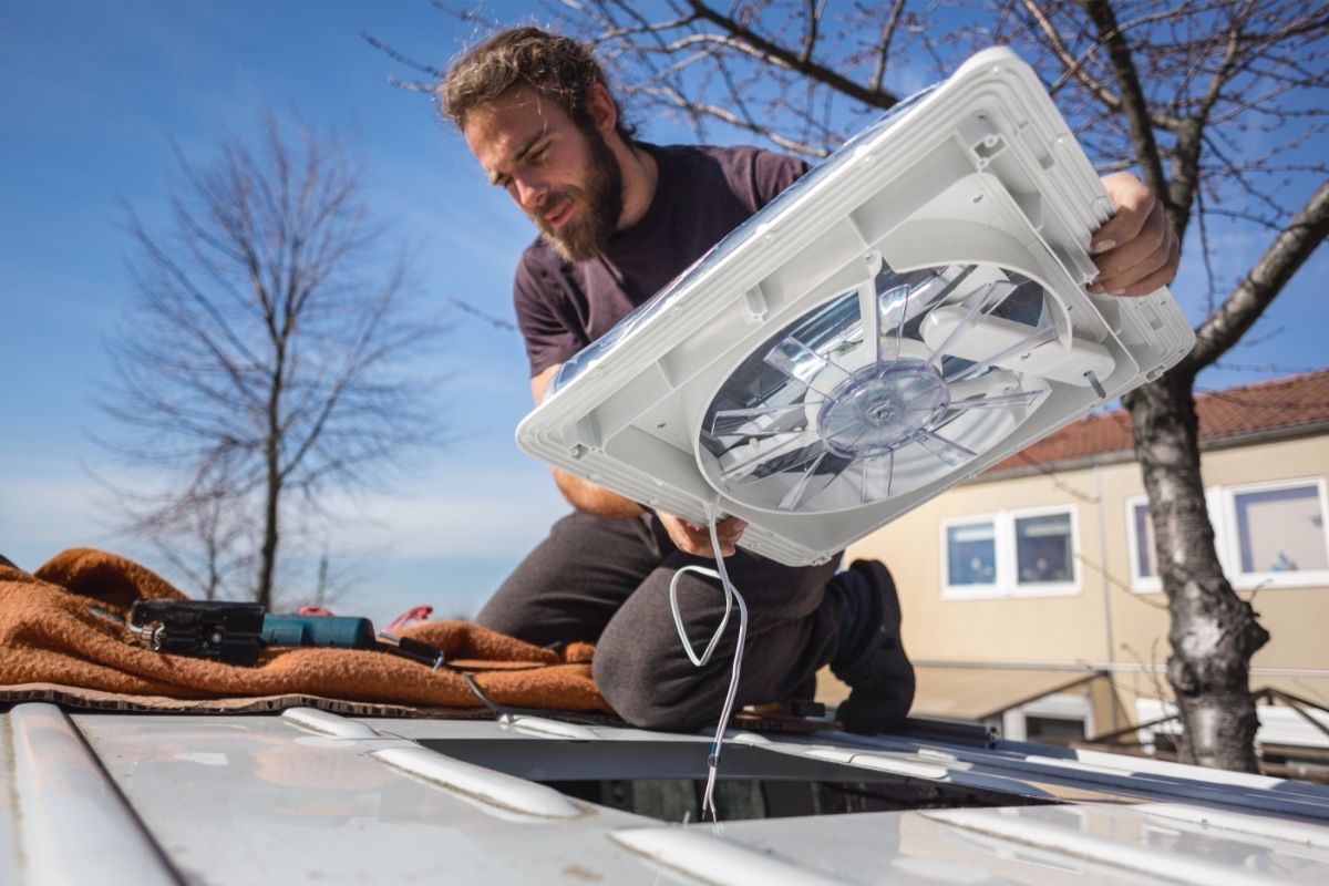 Man installing a fan on the roof of his van