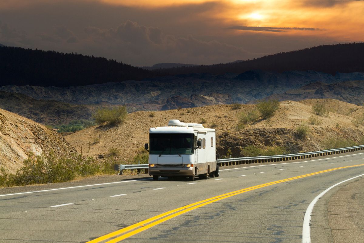 An RV heads down the road at sunset